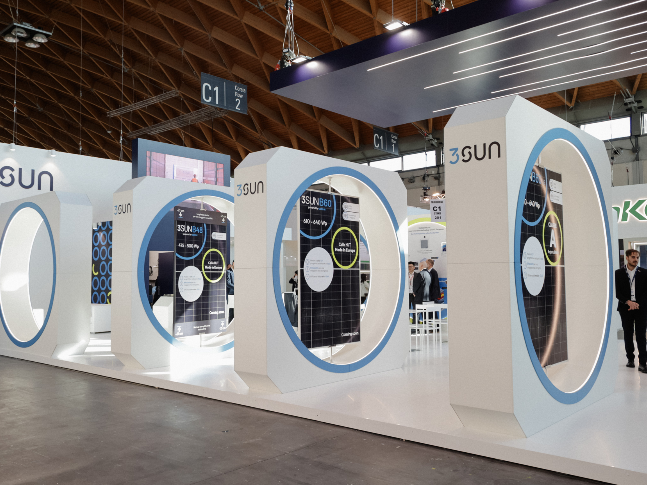 Exhibition booth of the company 3SUN with solar panels displayed inside large white structures with circular shapes