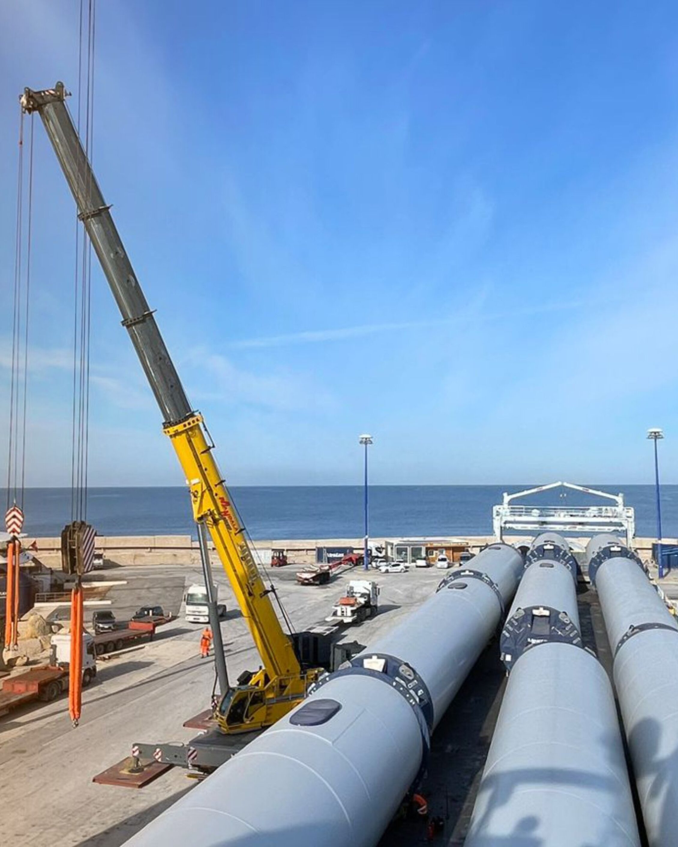 Industrial components and cranes at the port with the sea in the background