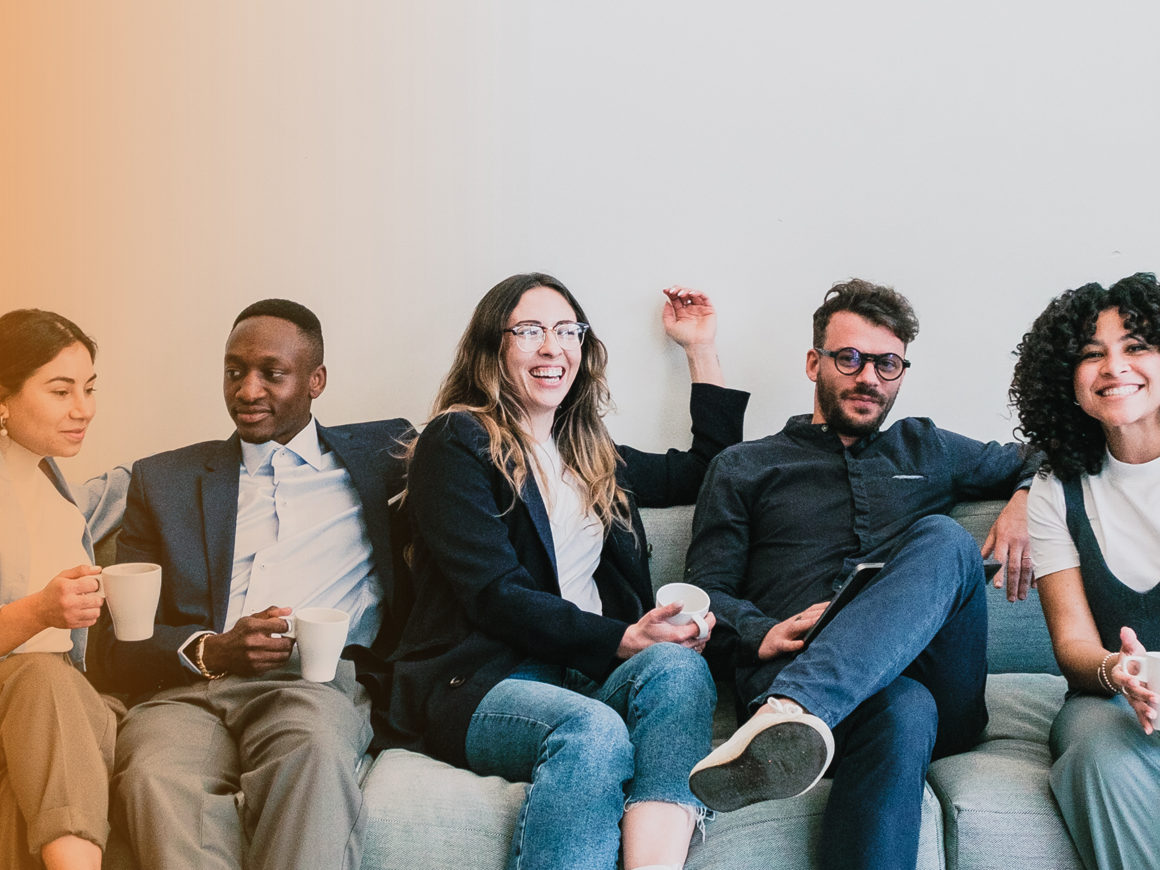 five smiling students sitting on a sofa