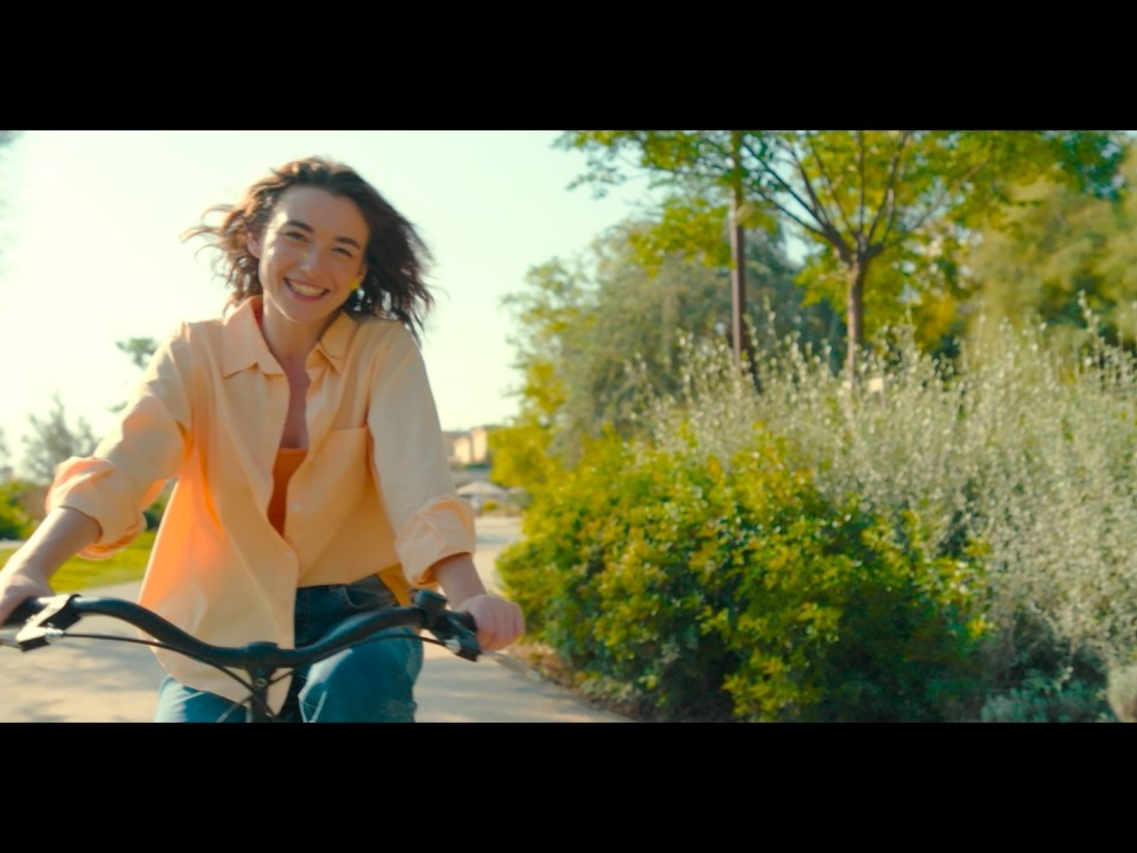 promotional video cover image by VisitRimini featuring a young woman cycling through the city